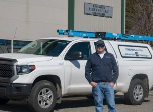 Matt Fronius electrician standing in front of company truck and warehouse